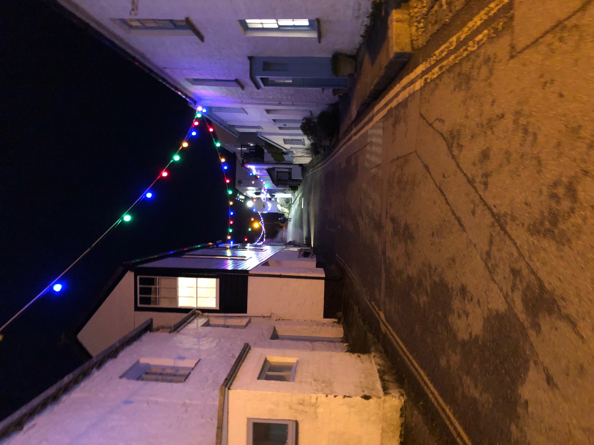 Portscatho’s cottages beneath colourful Christmas lights at night