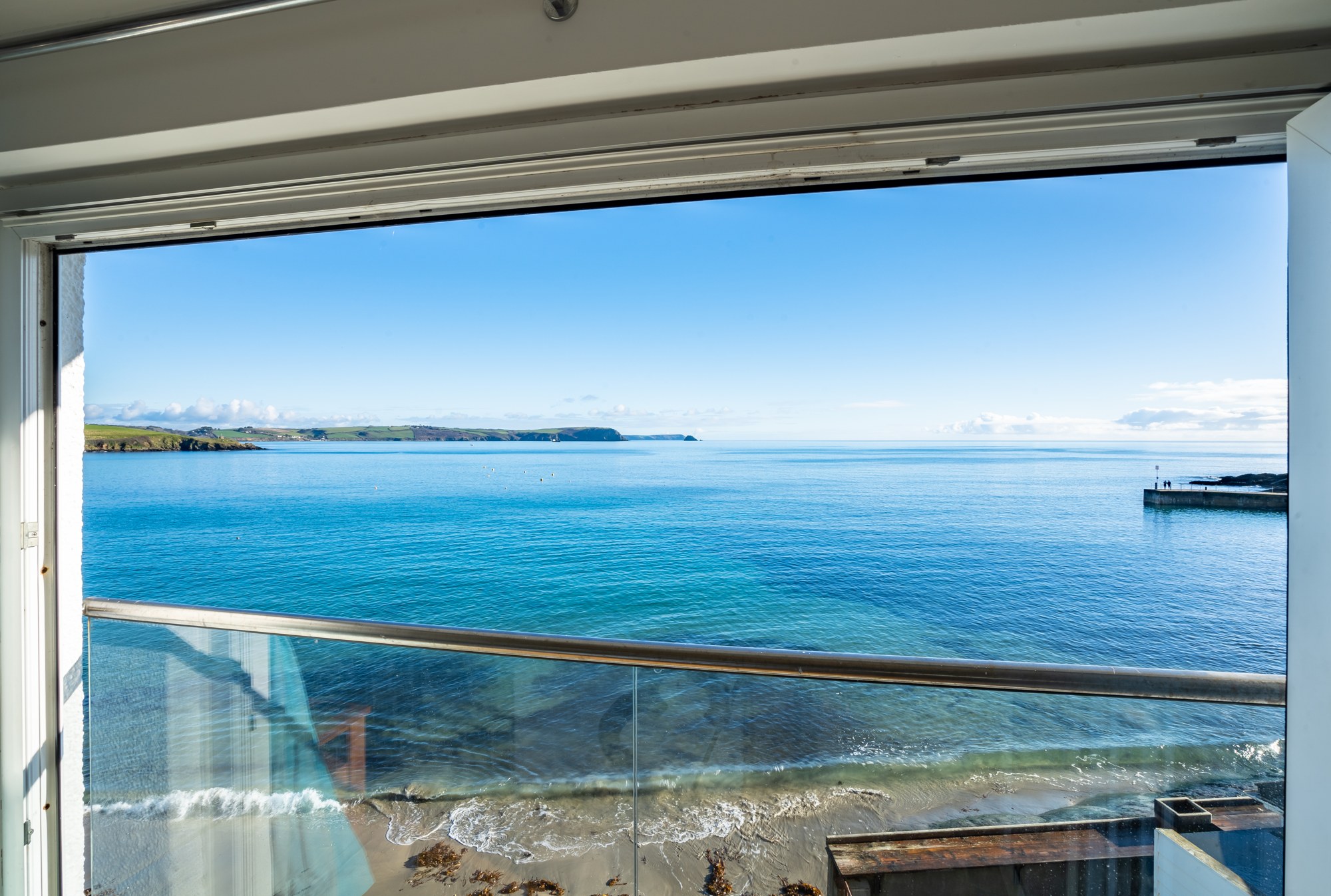Blue sea and the coastline seen through Top Deck's open balcony doors